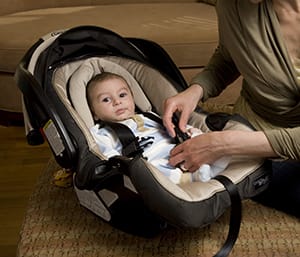 Person securing baby in carrier.
