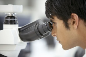 Person looking through lens of microscope